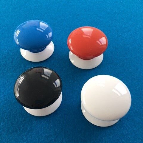 Auf einer dunkelblauen Filzunterlage liegen 4 FIBARO Button in Blau, Rot, Schwarz und Weiß.